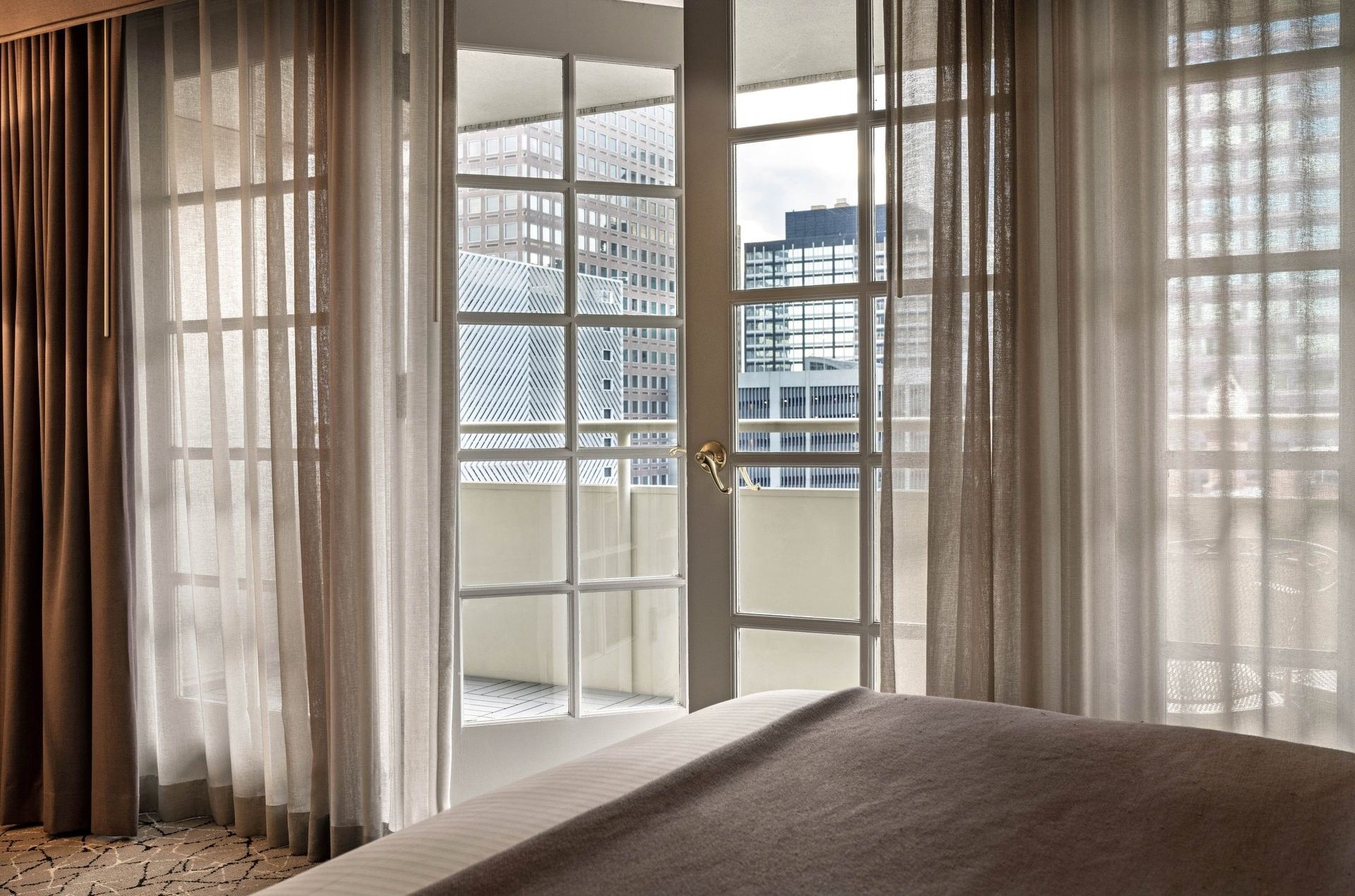 City views through open glass doors by sheer curtains in Deluxe Double Room at Warwick Denver