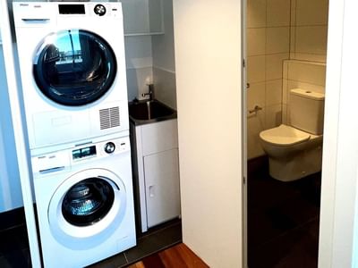 White washer and dryer in a bathroom with toilet at UniLodge at Curtin University Zamia Apartments.