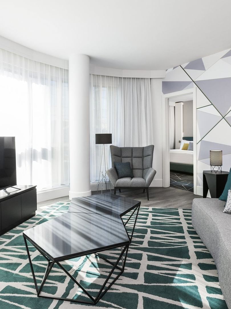 Espace salon avec canapé, télévision et fauteuil confortable dans la suite Crystal du Warwick Le Crystal