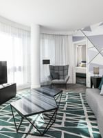 Espace salon avec canapé, télévision et fauteuil confortable dans la suite Crystal du Warwick Le Crystal