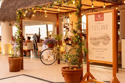 The elegant, warmly lit outdoor entrance area of a fine dining establishment at dusk.