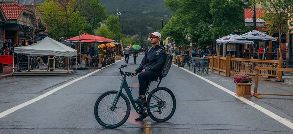 A person sits on their bike in the middle of the street in Canmore on a rainy day.