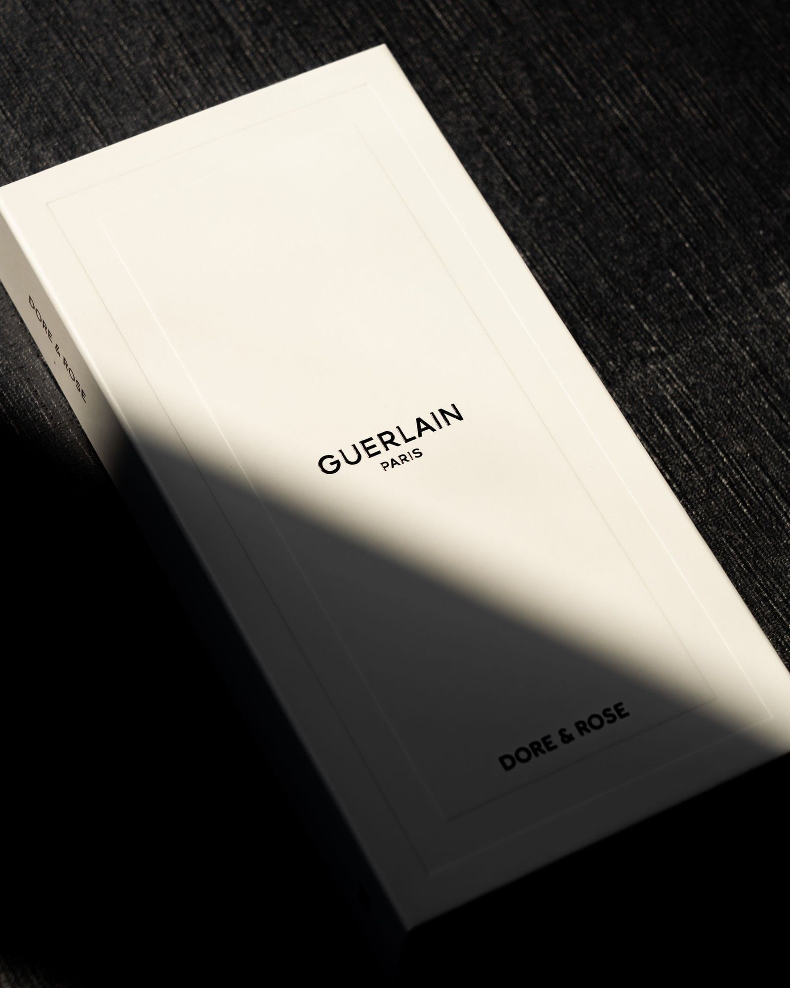Guerlain Paris gift box labeled Dore & Rose, resting on a dark linen surface under warm soft light at Hotel X Toronto
