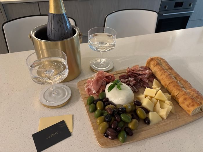 A spread with a bottle of champagne, two cocktails, cured meats, cheeses, olives served at ReStays Ottawa