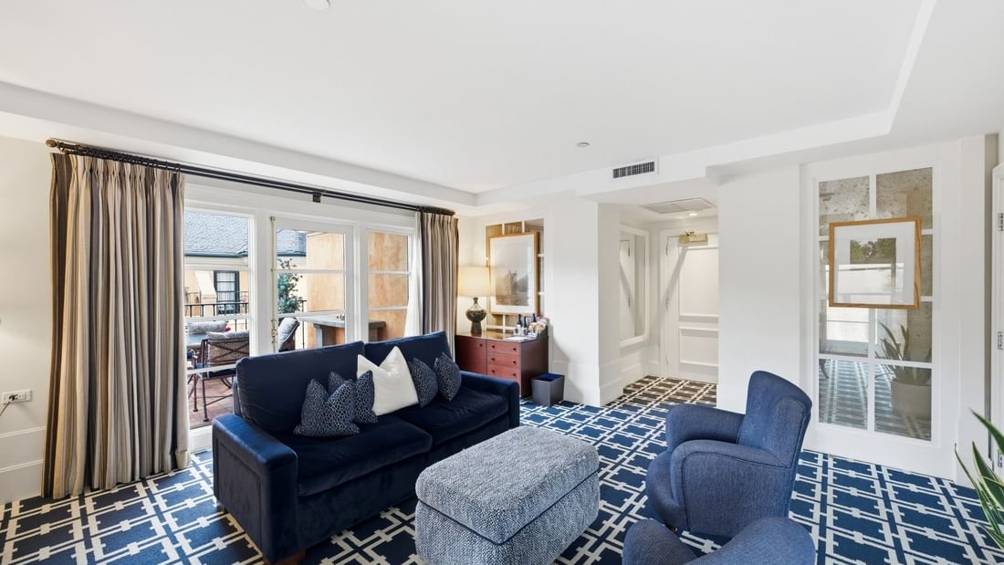Penthouse living area with navy sofa, patterned carpet, and balcony access at el PRADO Hotel in Palo Alto.