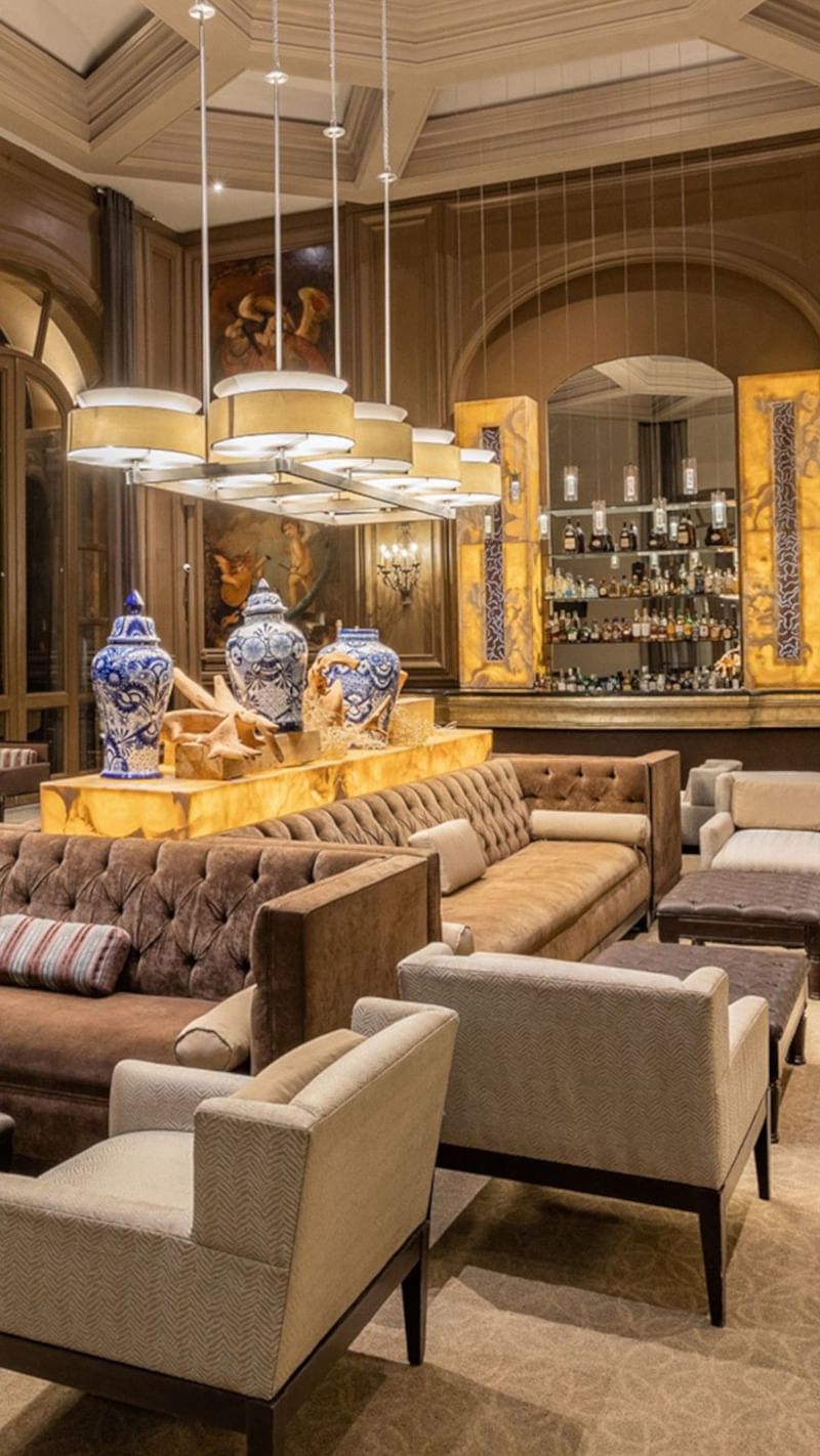 Bar Los Murales with tufted brown sofas, blue ceramic vases, and warm ambient light at Quinta Real Monterrey