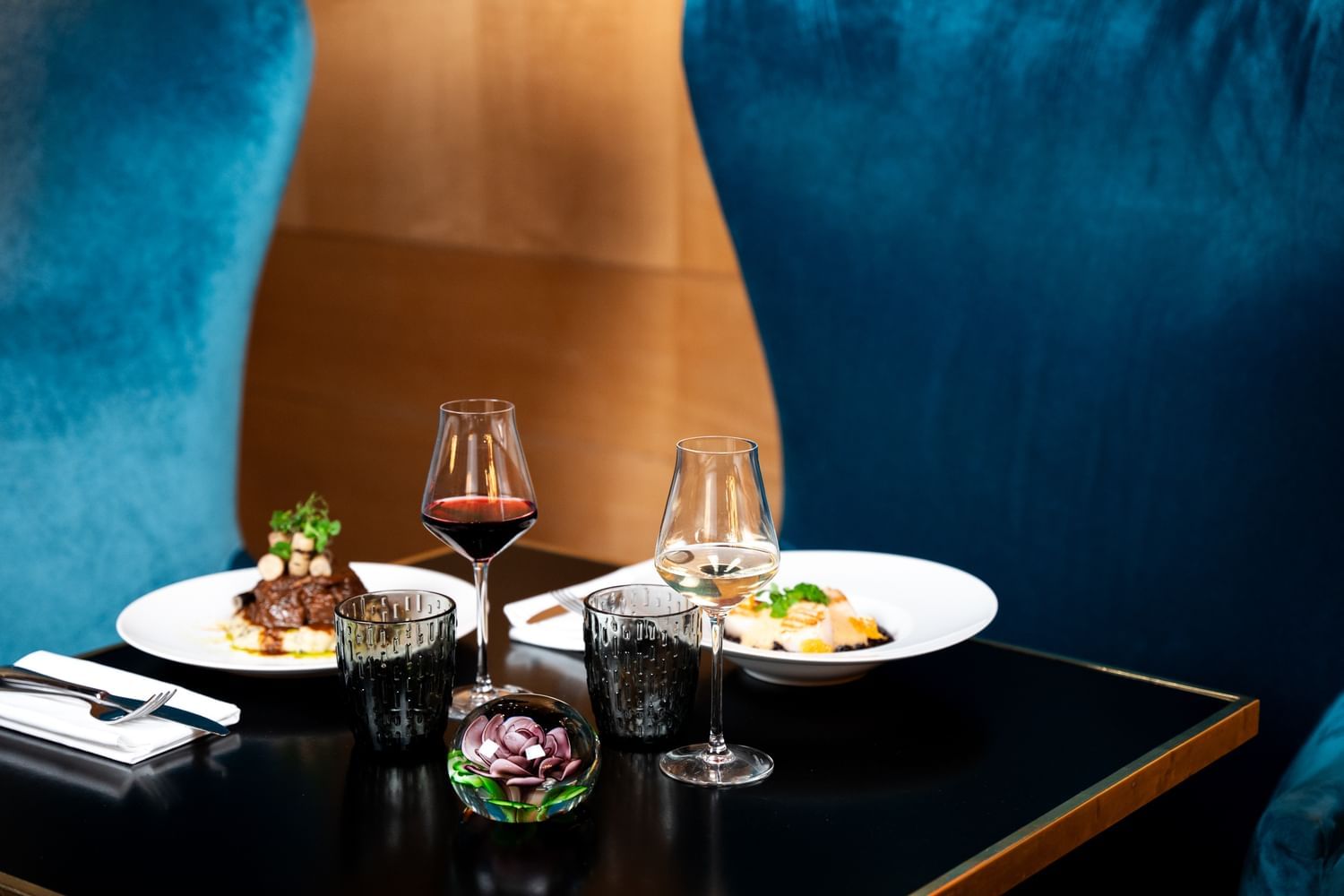 Dining setup with two gourmet plates, and red and white wine glasses served in Restaurant Le W