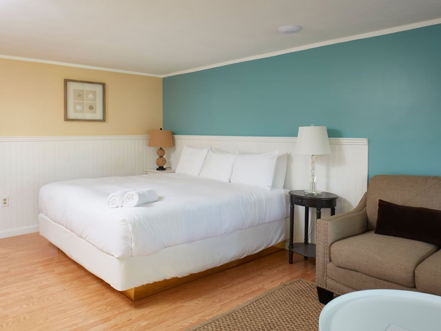 Bed with table lamp by the sofa and wooden floors in Maria Cottage Suite at Breezeway Boutique Hotel