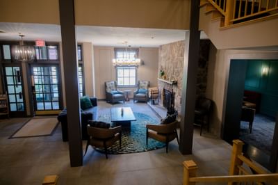 Cozy lounge area with armchairs and a coffee table near a stone fireplace in the spacious lobby at La Tourelle Hotel and Spa