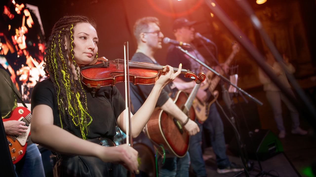 Musicians performing on stage with a violinist at the forefront during Coldsnap event.