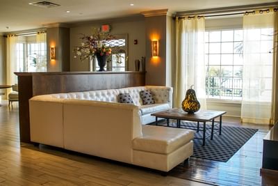 A white leather sofa at The White House Hotel lobby with large windows, sheer curtains, and warm wall lighting