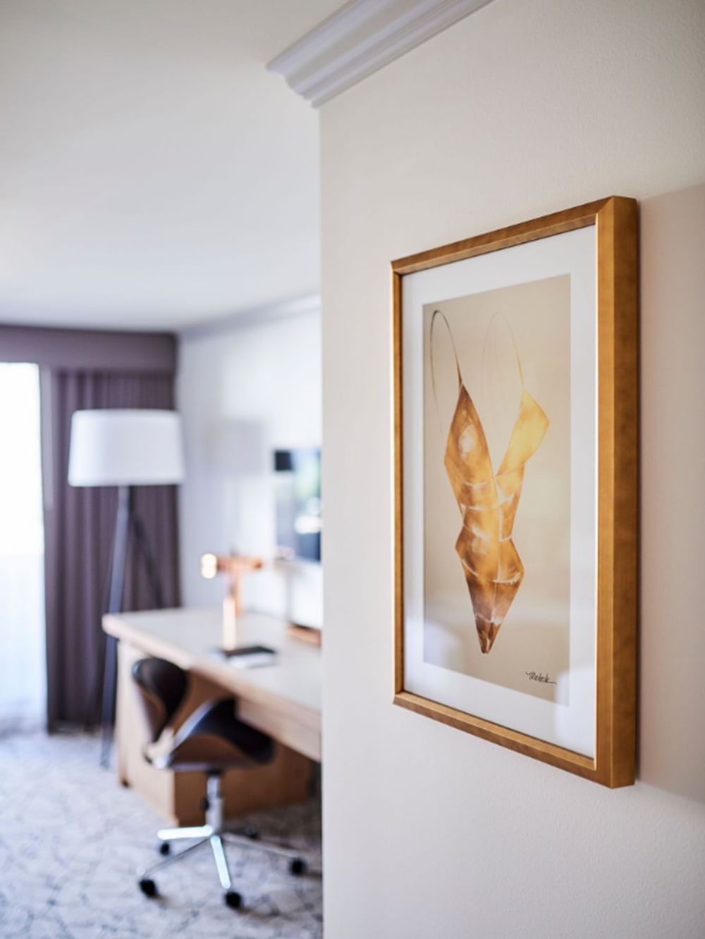 Gold framed swimsuit artwork by a work desk under soft lighting in Classic Rooms at Warwick Denver