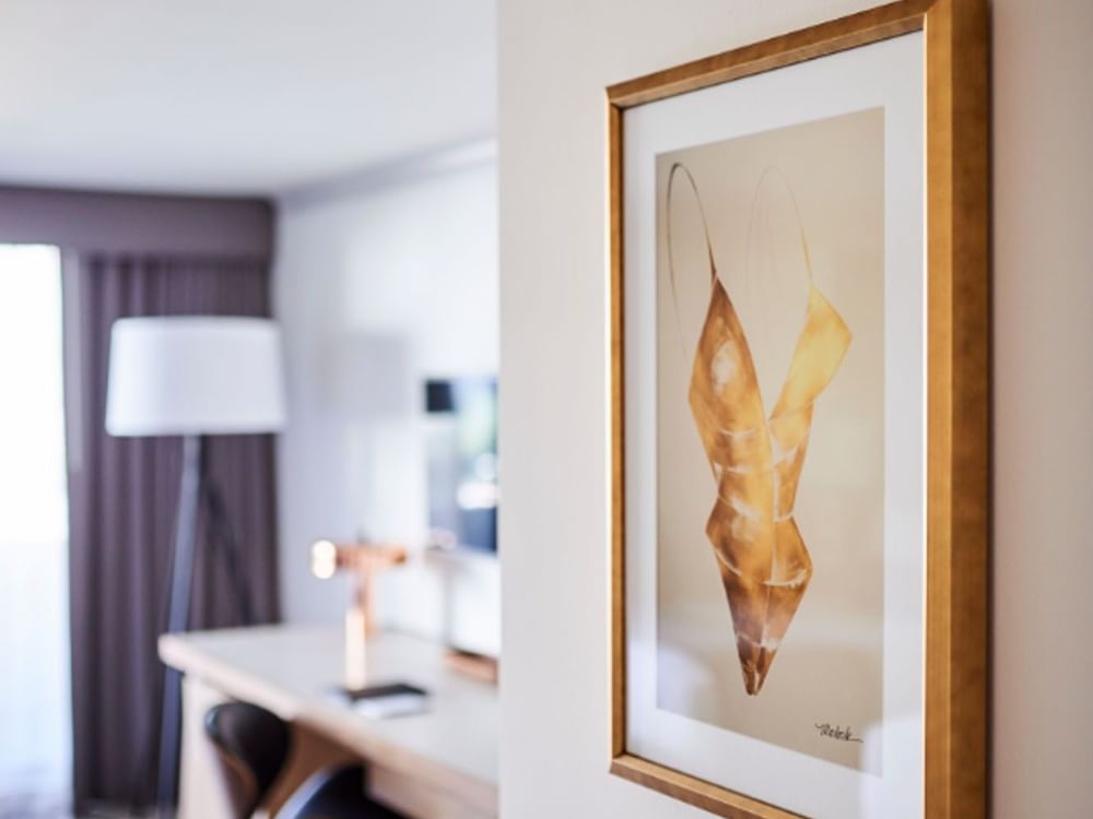 Gold framed swimsuit artwork by a work desk under soft lighting in Classic Rooms at Warwick Denver