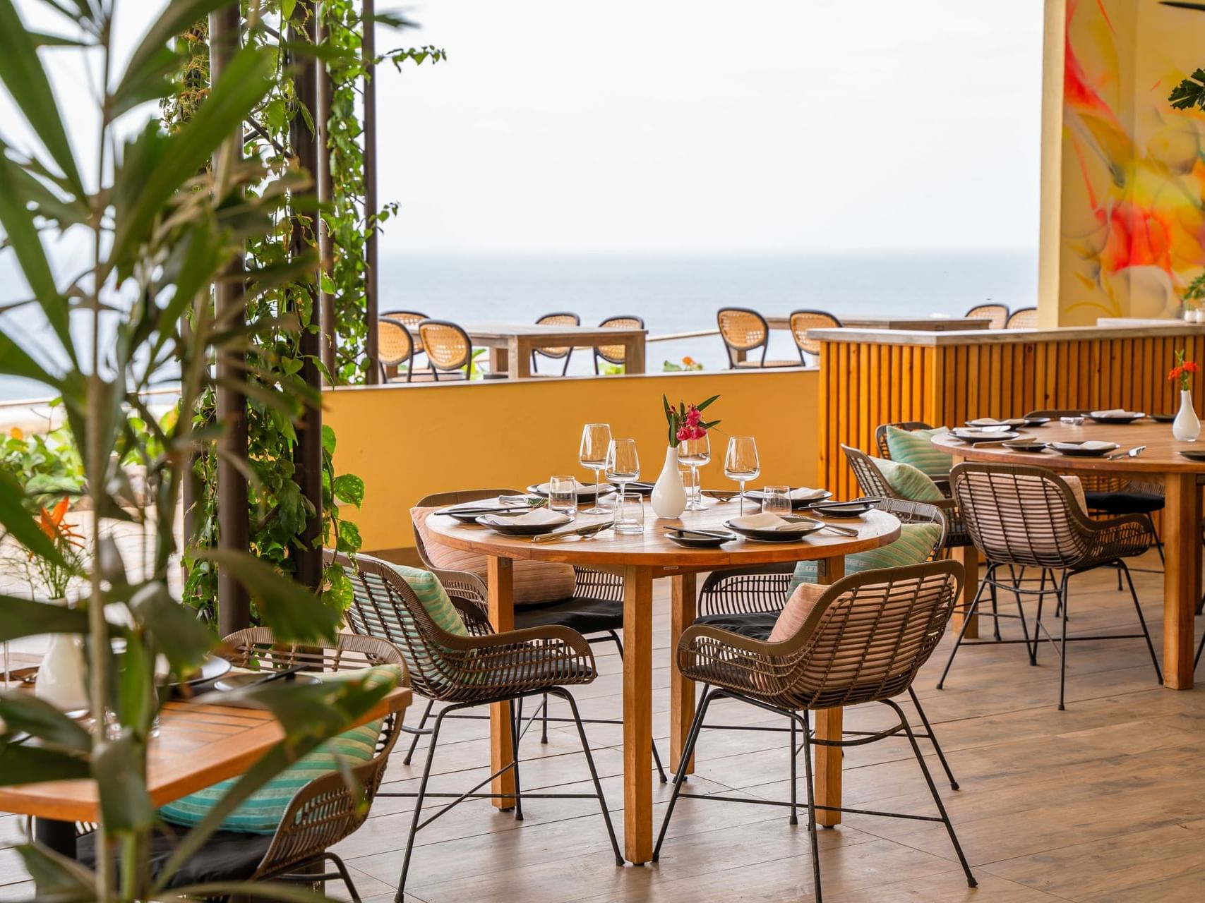 Dineren met uitzicht op de oceaan bij Bobbie’s Beach Club, met tafels en groen en kleurrijke decoratie, Golden Rock Resort