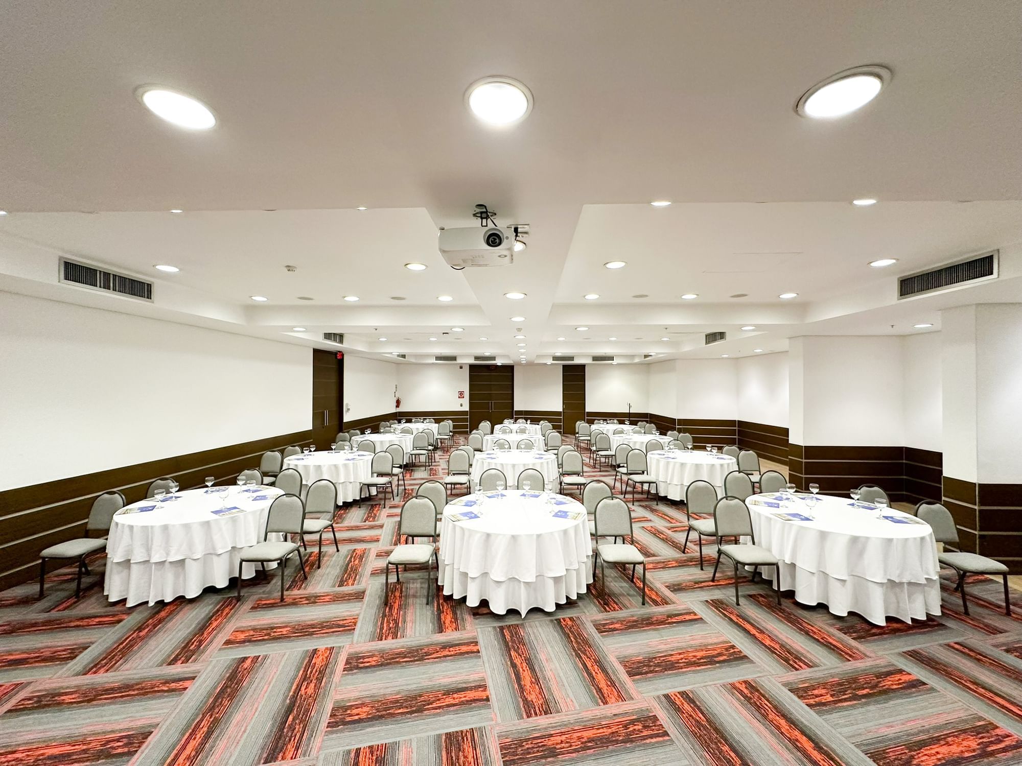 Round tables arranged on the carpeted floor in Corales at San Fernando Plaza Hotel