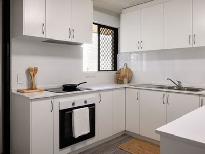 Clean kitchen with white cabinets, stove, sink, and window at UniLodge at Curtin University - Guild House.