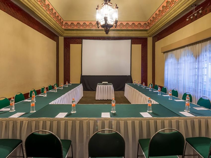 Large U-shaped conference table with green chairs and white linens in Salón Marqués at Quinta Real Aguascalientes