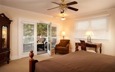 A spacious bedroom at The Stanley Hotel with a large bed, a desk and a balcony in Presidential Cottage