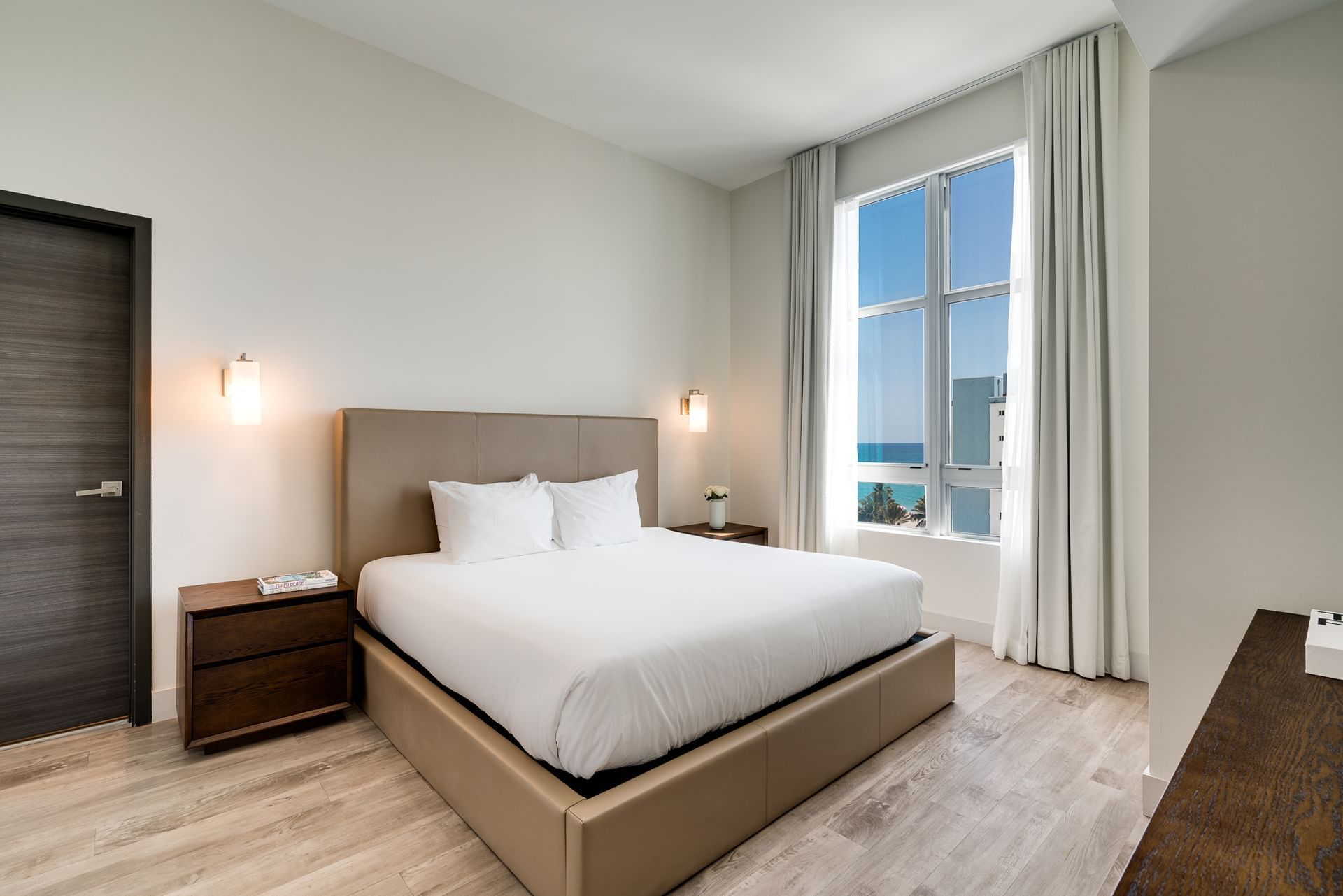 A clean and modern hotel room with a large bed, nightstands, and a window with a view.