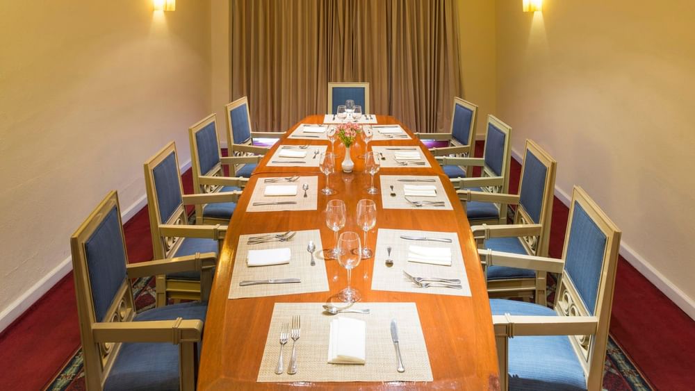 Intimate dining room featuring a long wooden table set for a fine meal at Camino Real Puebla Angelopolis