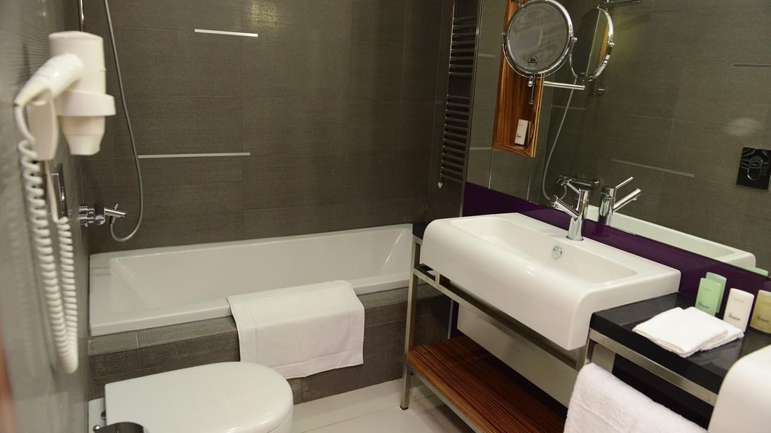White toilet by a soaking tub and vanity under a modern chrome faucet in Junior Suite at Warwick Stone 55 - Beirut