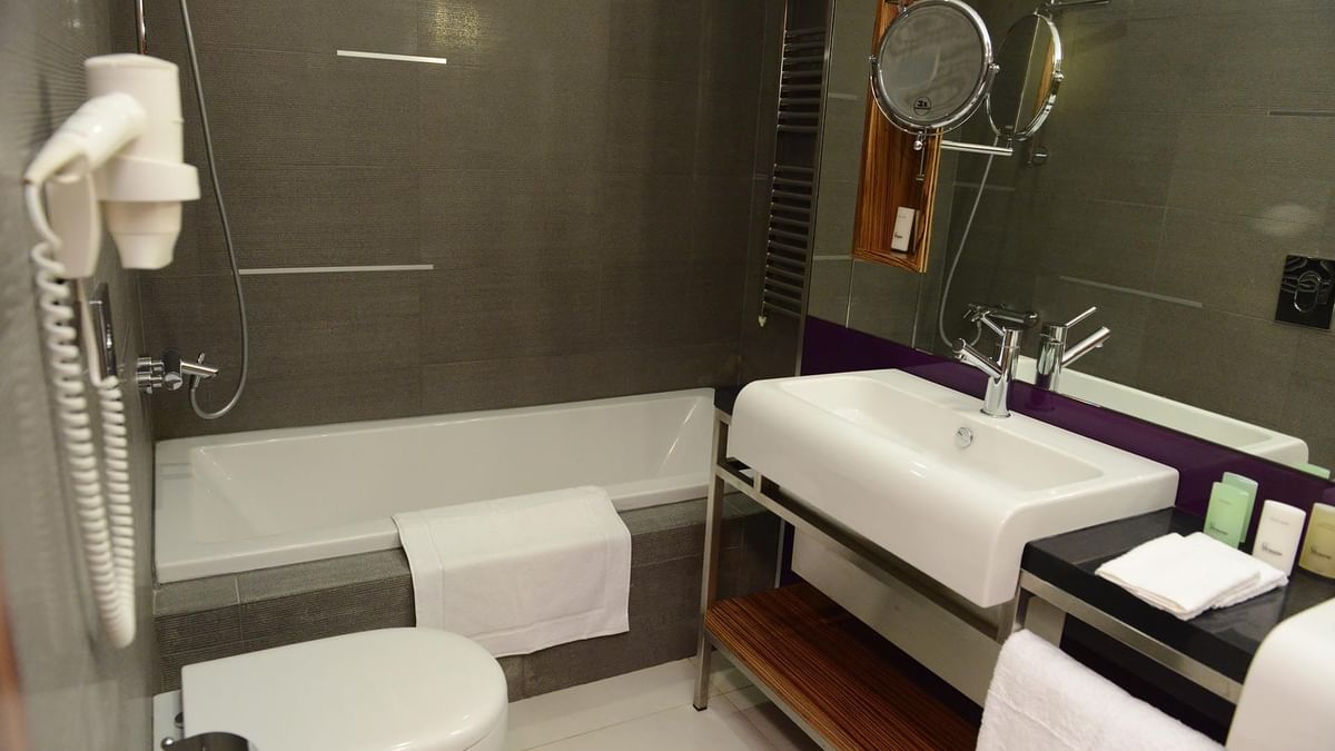 White toilet by a soaking tub and vanity under a modern chrome faucet in Junior Suite at Warwick Stone 55 - Beirut