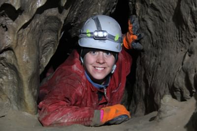 Person exploring a cave with a helmet and headlamp at Canmore Cave Tours near Clique Hotels & Resorts