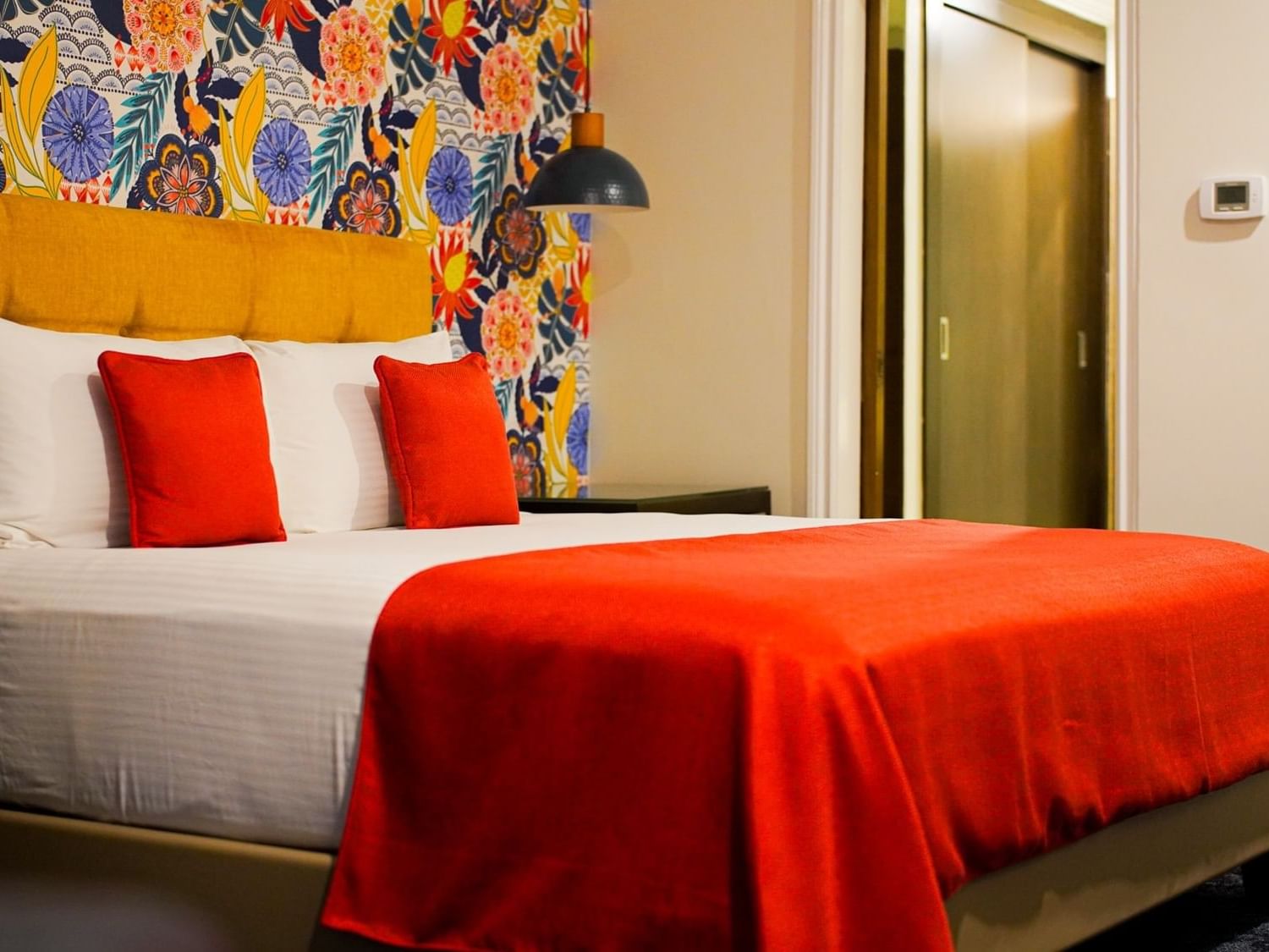 Plush king bed with pillows behind colorful wallpaper in Royal Two Bedroom Suites at Jamaica Pegasus Hotel