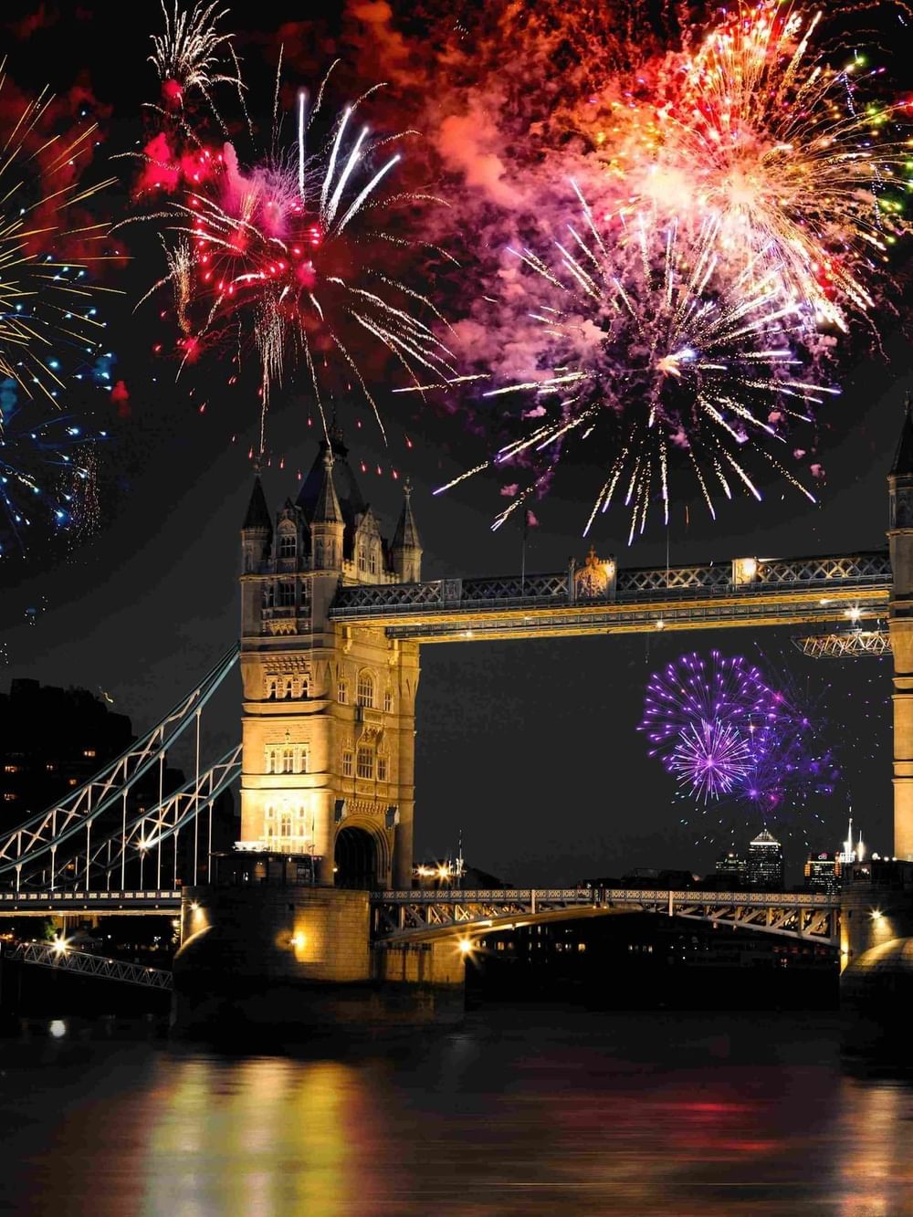 New Year fireworks lighting up the sky near Tower Bridge with reflections on the water near Warwick Hotels & Resorts