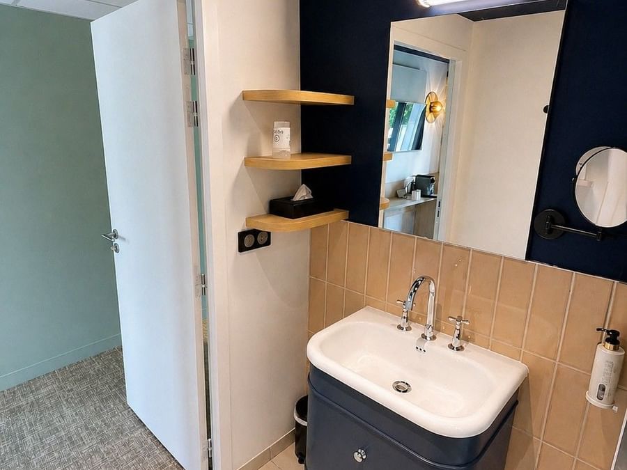 Salle de bain élégante avec lavabo et miroir dans la Suite Junior à Osmo Hôtel Chantepie.