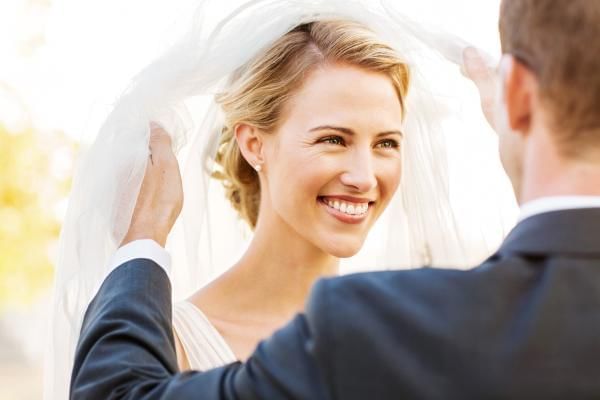 Groom lifting brides veil at alter