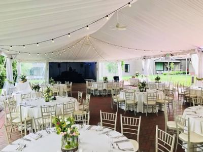 Elegant white tent with gold chiavari chairs set for a wedding reception at Aramark Chauncey Conference Center