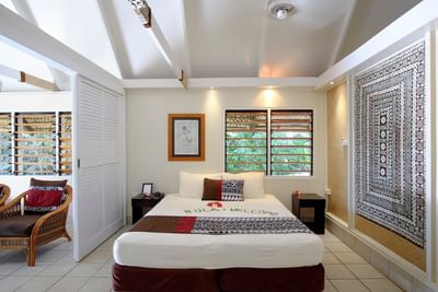 Lagoon Bures room with a bed, artwork, and tropical windows at Musket Cove Island Resort & Marina