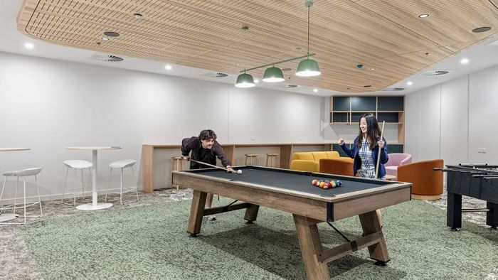 Residents playing pool and table football in entertainment space at UniLodge Brisbane City.