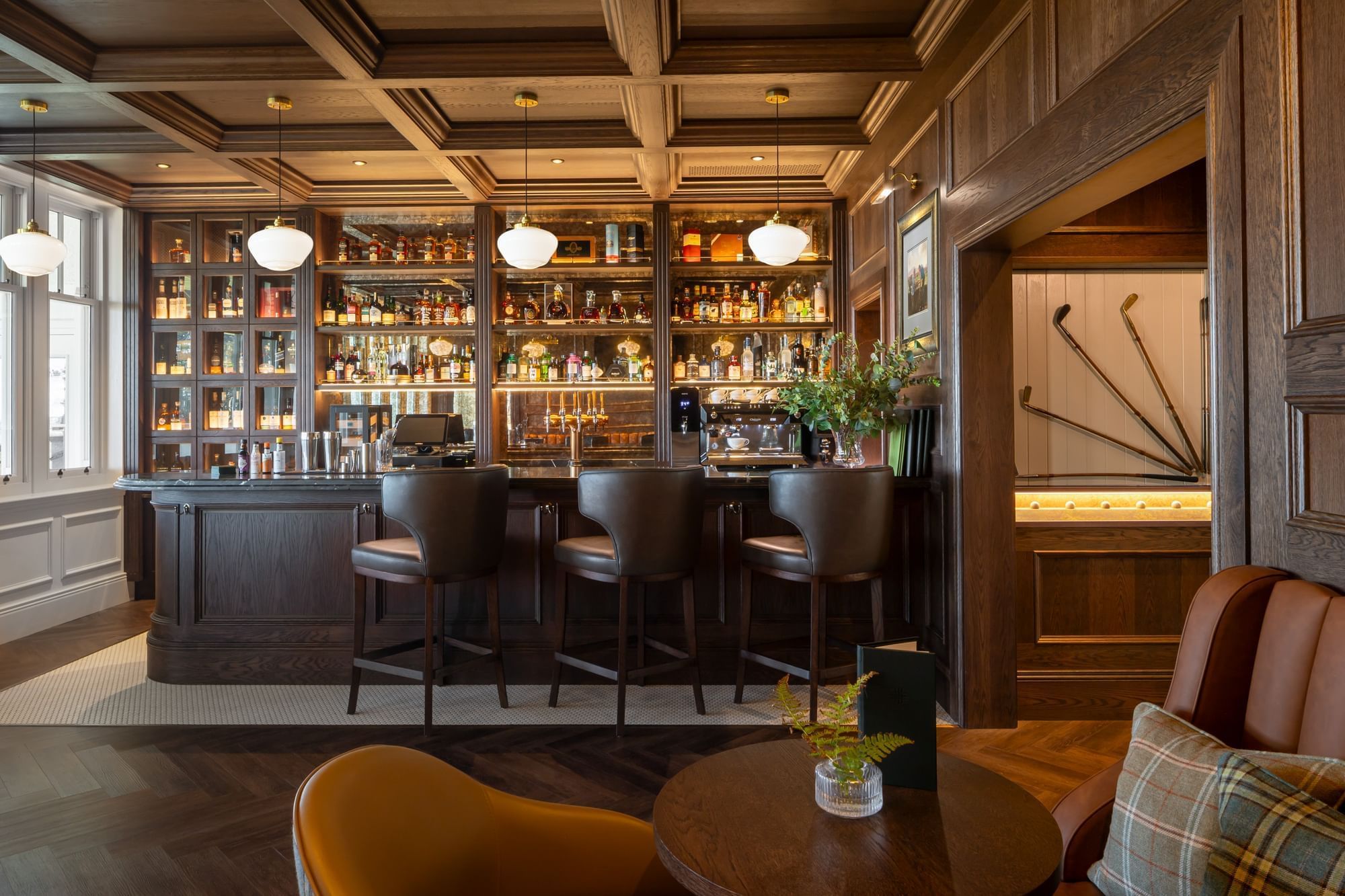 Luxurious hotel bar with a mahogany counter, leather stools, and a well-stocked liquor wall at Dunluce Lodge