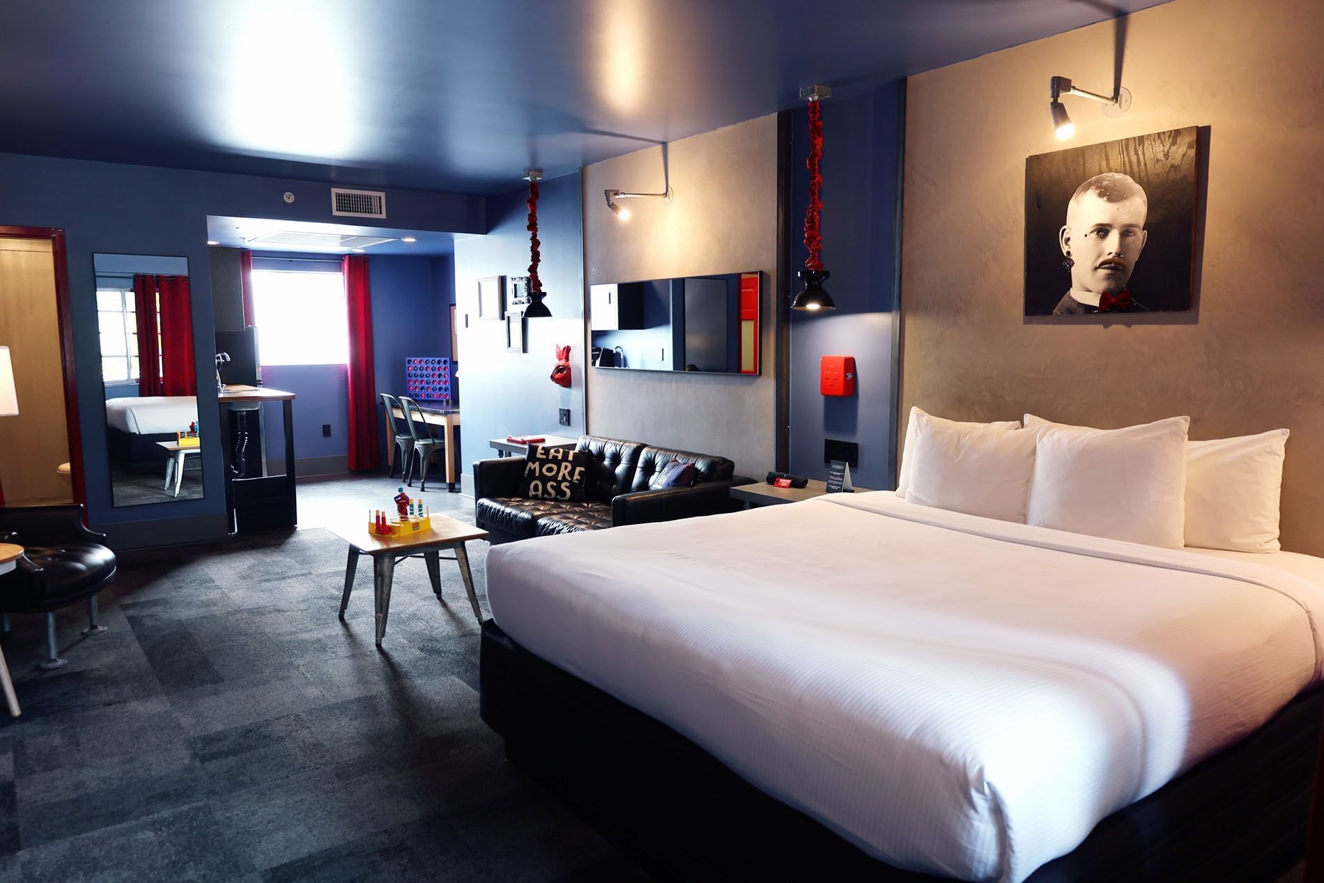 A wide view of a hotel room with a king-size bed, a sofa, a flat-screen TV, and a small dining table.