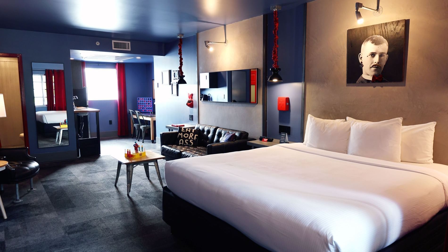 A wide view of a hotel room with a king-sized bed, sofa, desk, and TV.