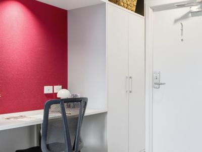 A cozy desk area with a chair and red wall at UniLodge Auckland City.
