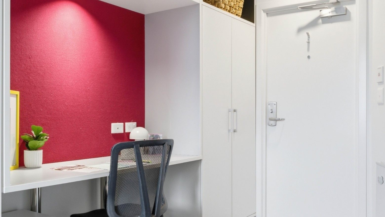 A cozy desk area with a chair and red wall at UniLodge Auckland City.