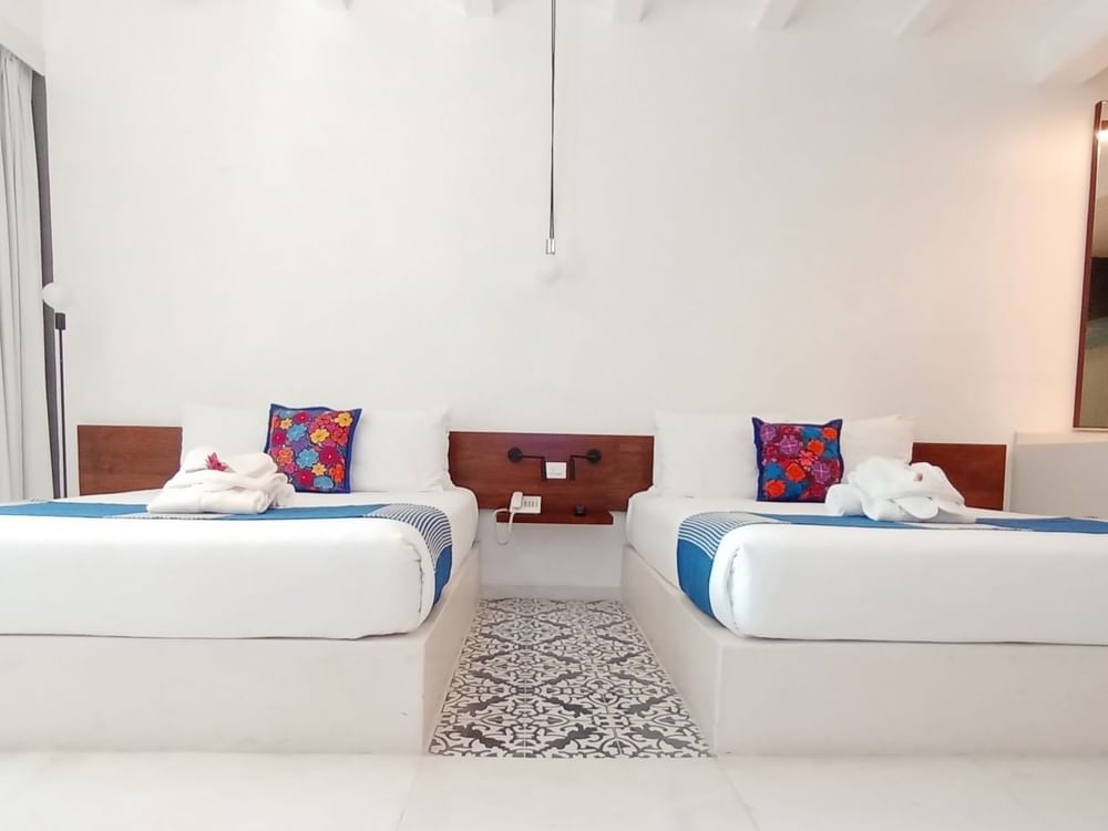 Two queen beds in Deluxe Room with carpeted floors at Huayacán Cuernavaca Curamoria Collection