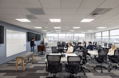 Modern office space with people at desks and a presenter at a whiteboard at Aramark Ross