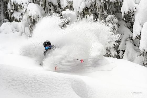 A man is skiing in the deep snow near Aava Whistler Hotel