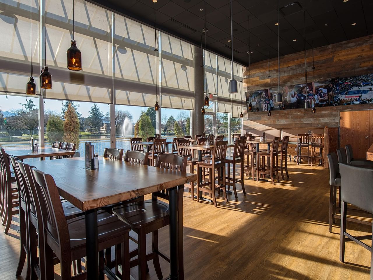 Dining area with wooden tables and chairs, large windows, and a view of the pond at Coast Chilliwack Hotel by APA.