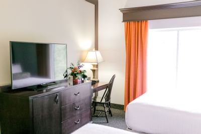 beds facing a television and window with orange curtains