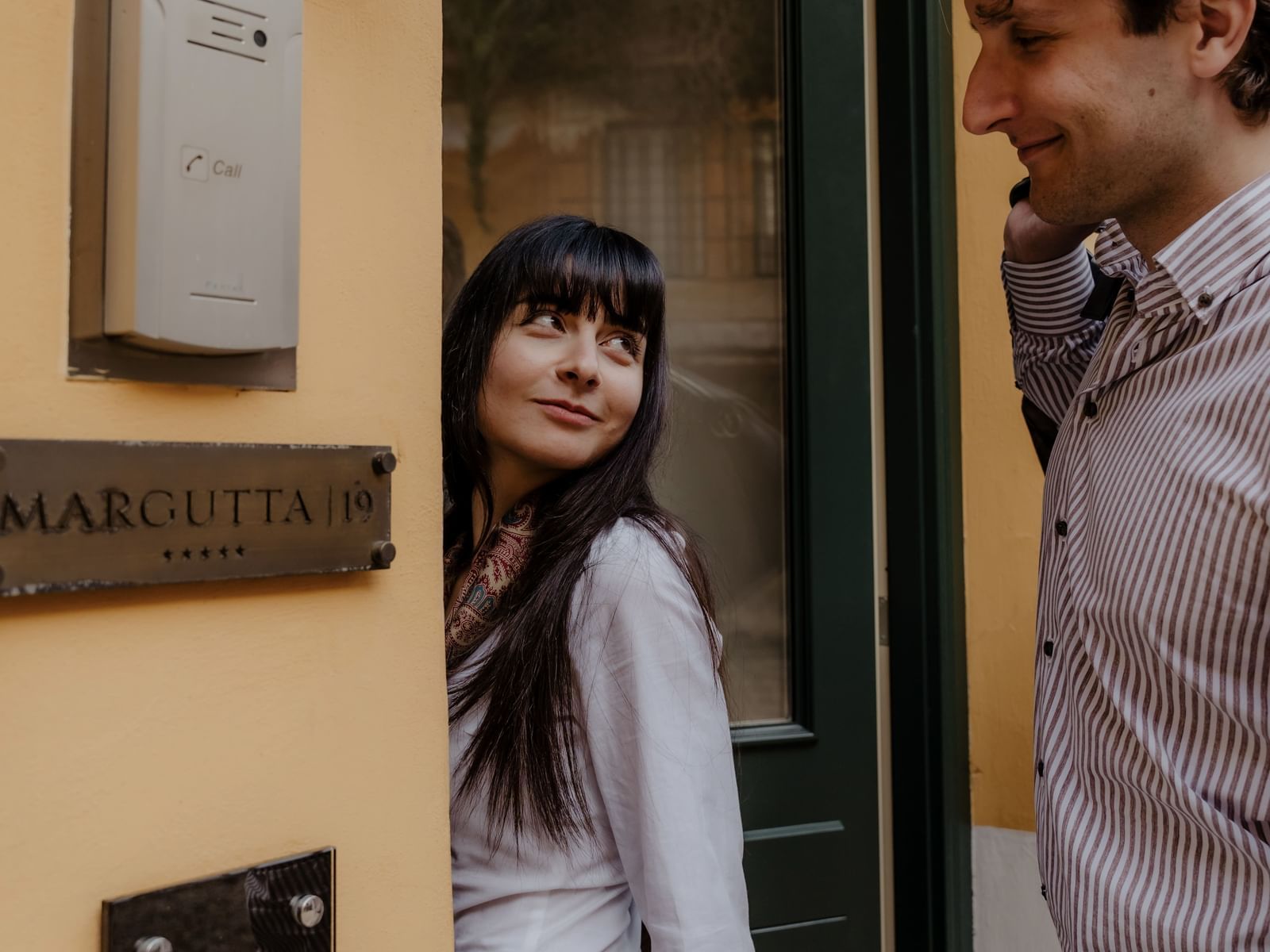 A couple standing by an entrance with an intercom at Margutta 19