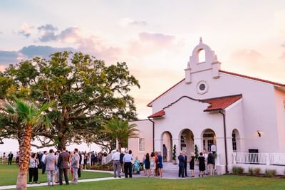 Guests mingling on the lawn outside the historic Chapel at sunset during a wedding reception at Centennial Plaza Resort