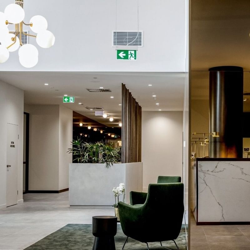 Modern BTR lobby with a marble reception desk, gold lamp, green armchair, and a decorative chandelier.