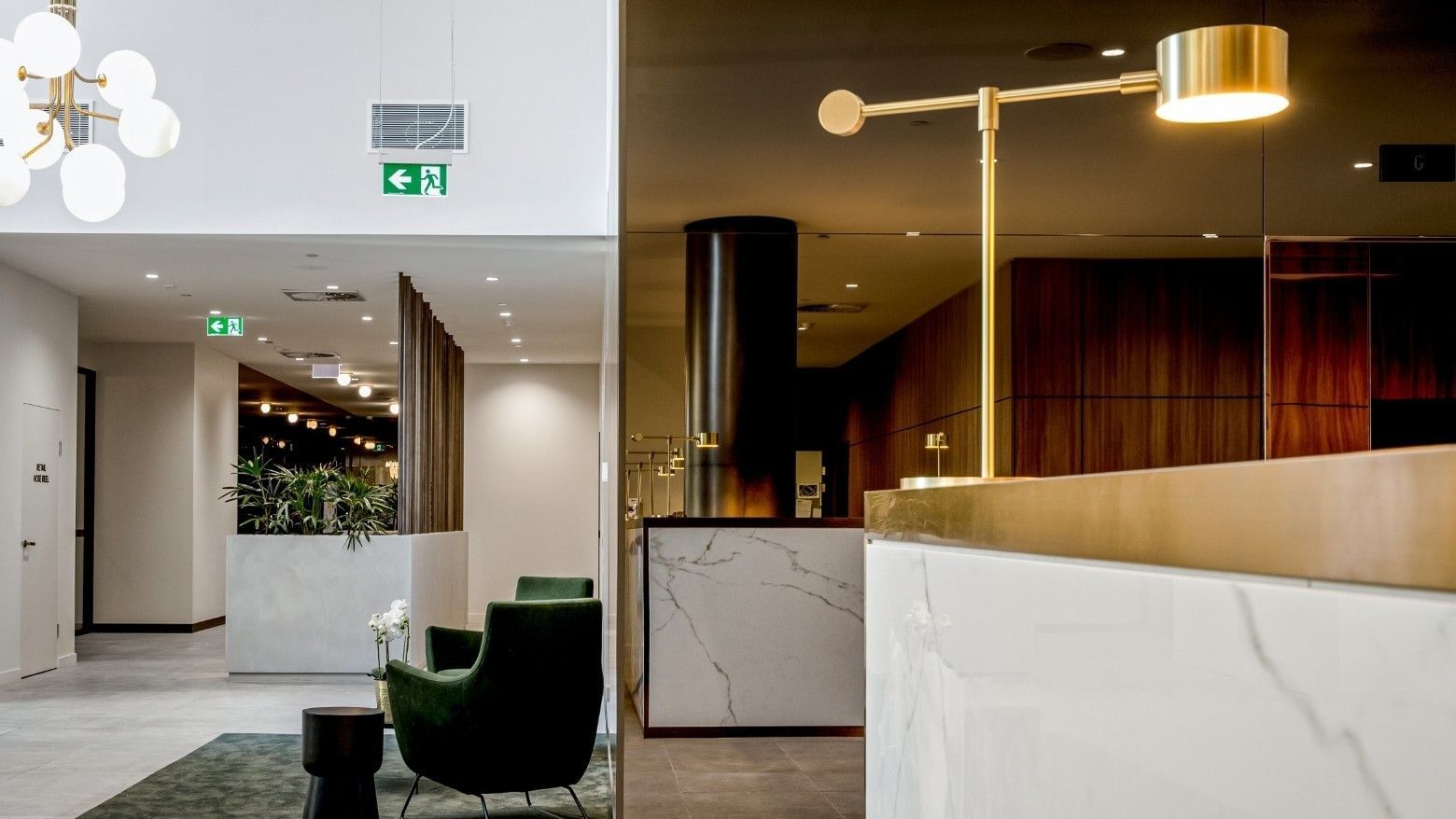 Modern BTR lobby with a marble reception desk, gold lamp, green armchair, and a decorative chandelier.