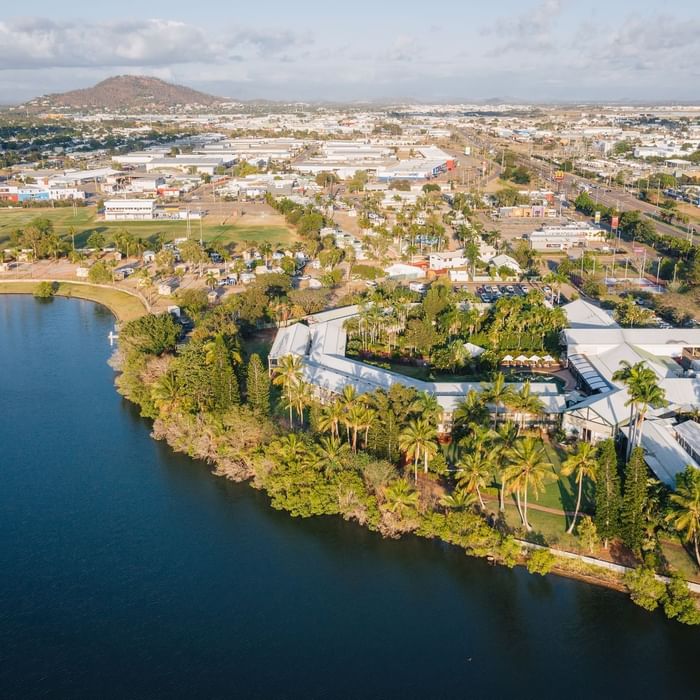 Aerial view of Mercure Hotel Townsville with a lake, palm trees against a mountain backdrop