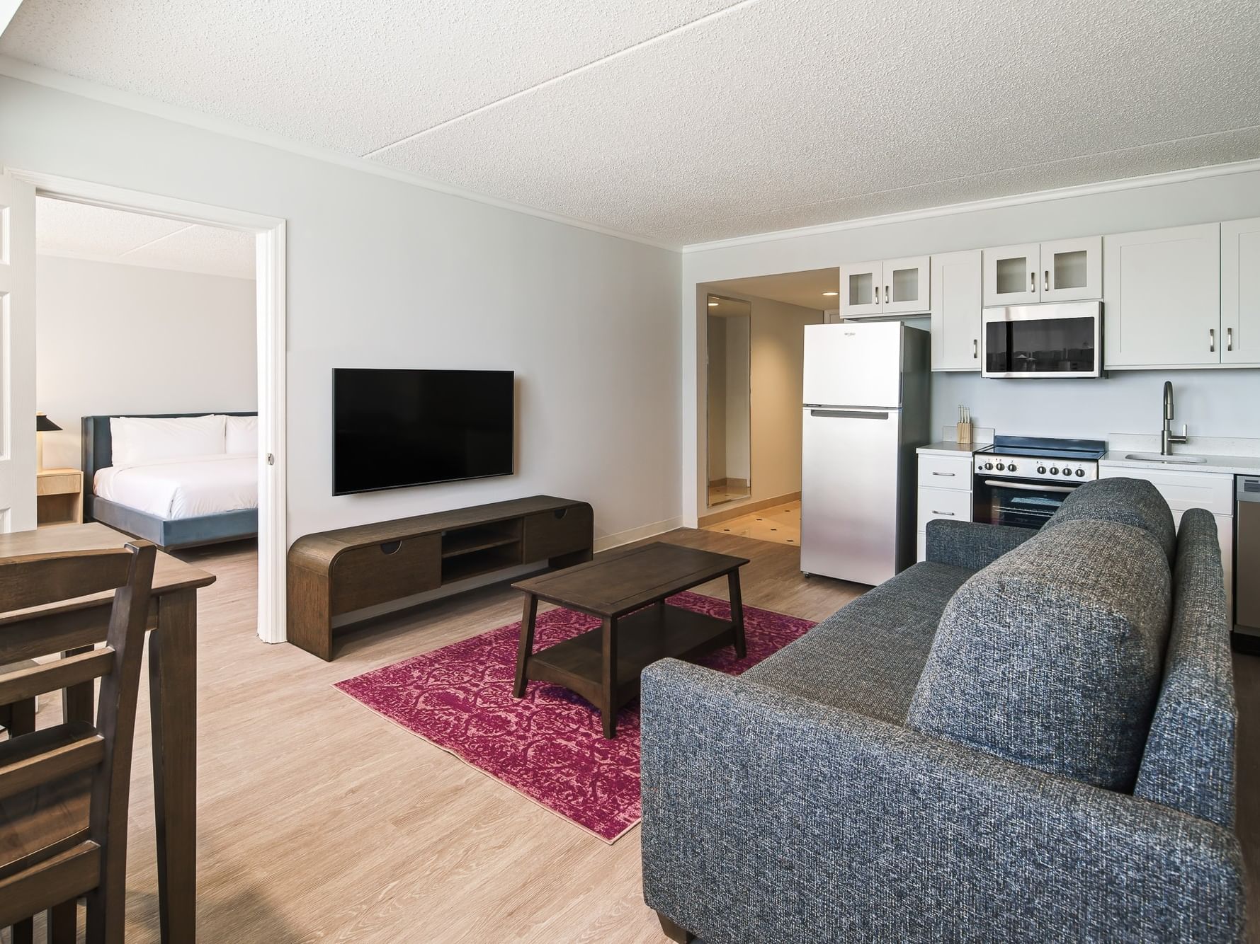 Open-plan living area with gray sofa, kitchen, and bedroom view at Showboat Hotel & Resort Atlantic City